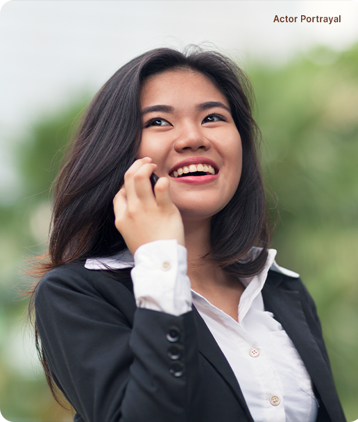 Actor Portrayal; A young, Southeast Asian woman, dressed smart casual, in a white blouse and black blazer, smiling while speaking on her cellphone.